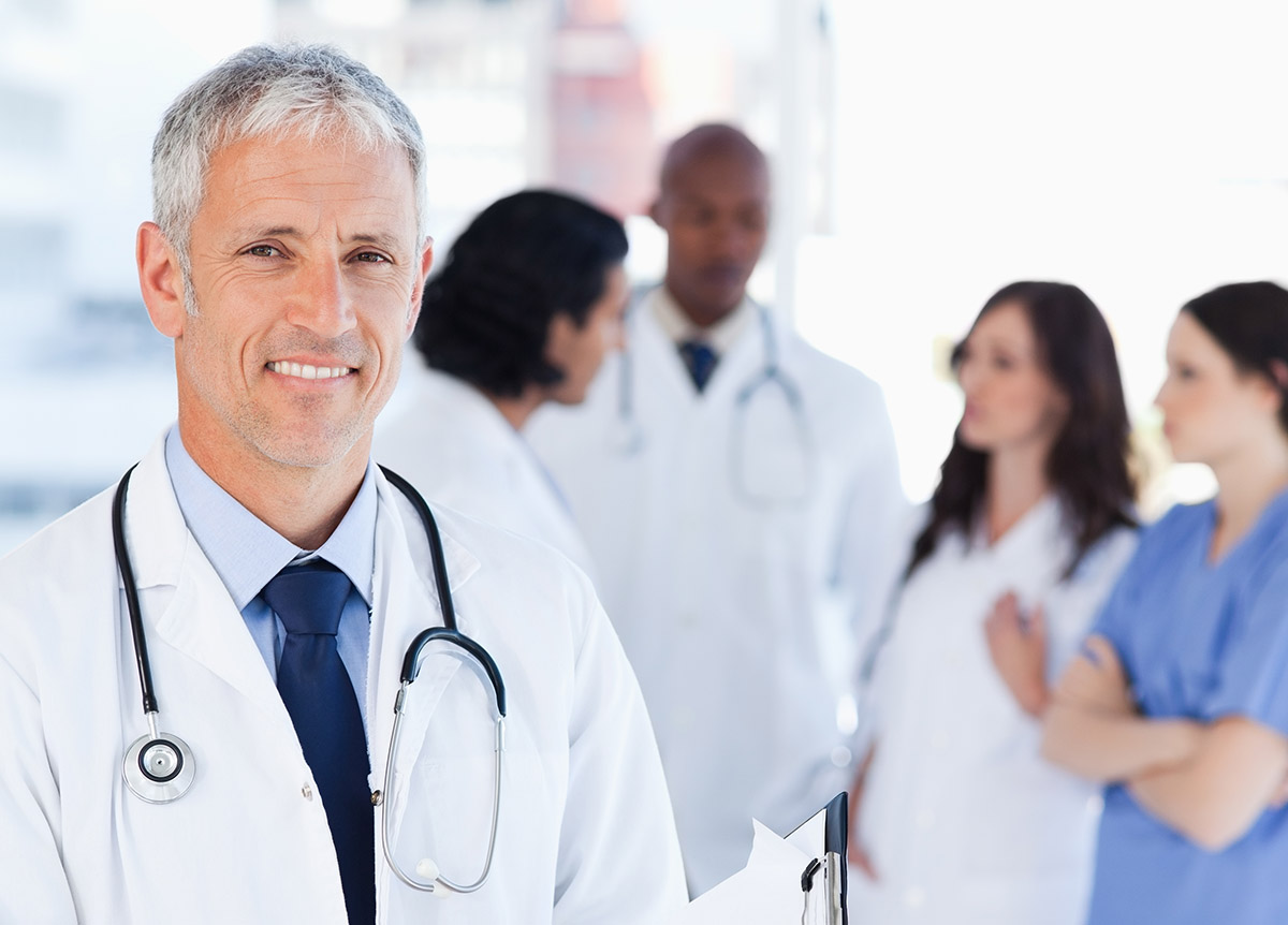 Mature doctor smiling while pointing to a sentence on his clipboard